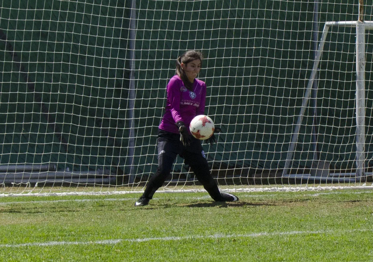 Jóvenes jugando fútbol en una cancha de pasto sintético