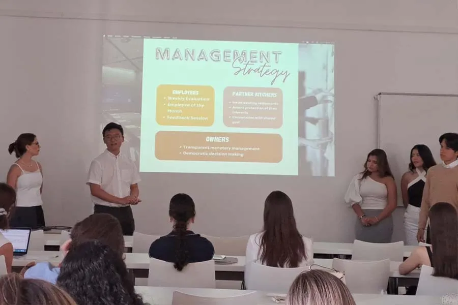 5 alumnos presentando al frente de un sal&oacute;n de clases. 