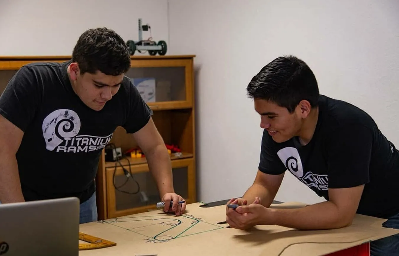 Alan trabajando colectivamente en un robot con su compa&ntilde;ero