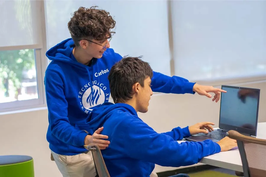 alumnos becados se&ntilde;alando una pantalla