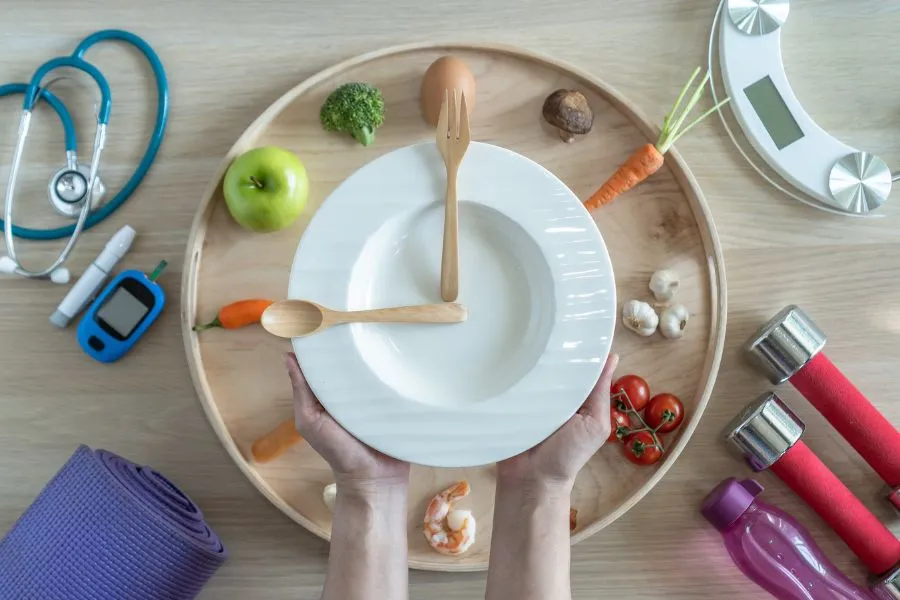 Fotograf&iacute;a conceptual con comida saludable, gluc&oacute;metro, tapete de yoga, pesas, bota con agua