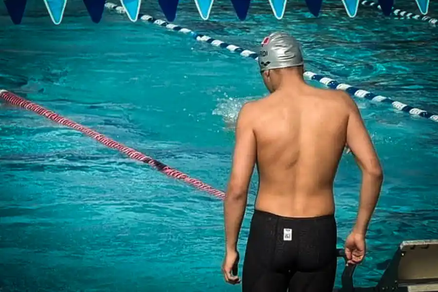 Diego Lizardi, nadador hidalguense y estudiante de PrepaTec, se prepara junto a la piscina antes de una competencia de nataci&oacute;n, vistiendo gorra plateada y traje de competici&oacute;n.
