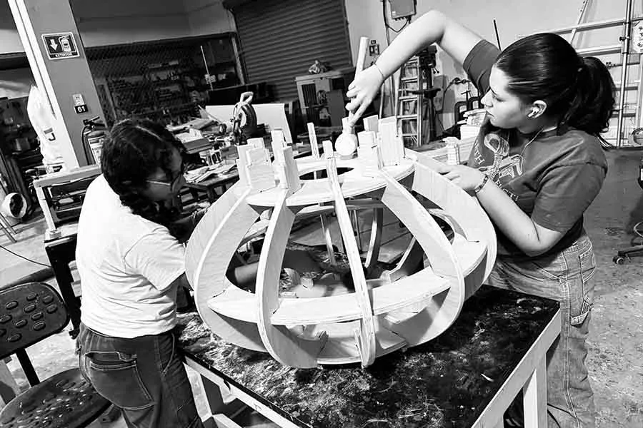 Dos chicas trabajan en una estructura de madera.