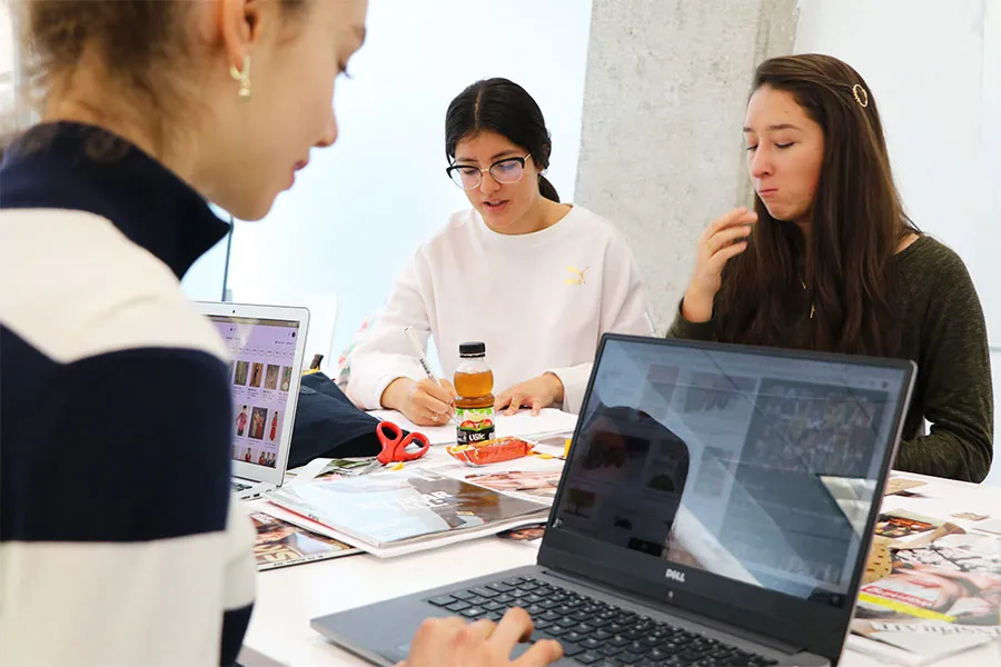 Alumnas  de estudios creativos dise&ntilde;ando e investigando en sus computadoras 