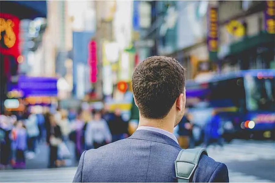 hombre dando la espalda, est&aacute; vestido con un traje y mirando hacia la calle