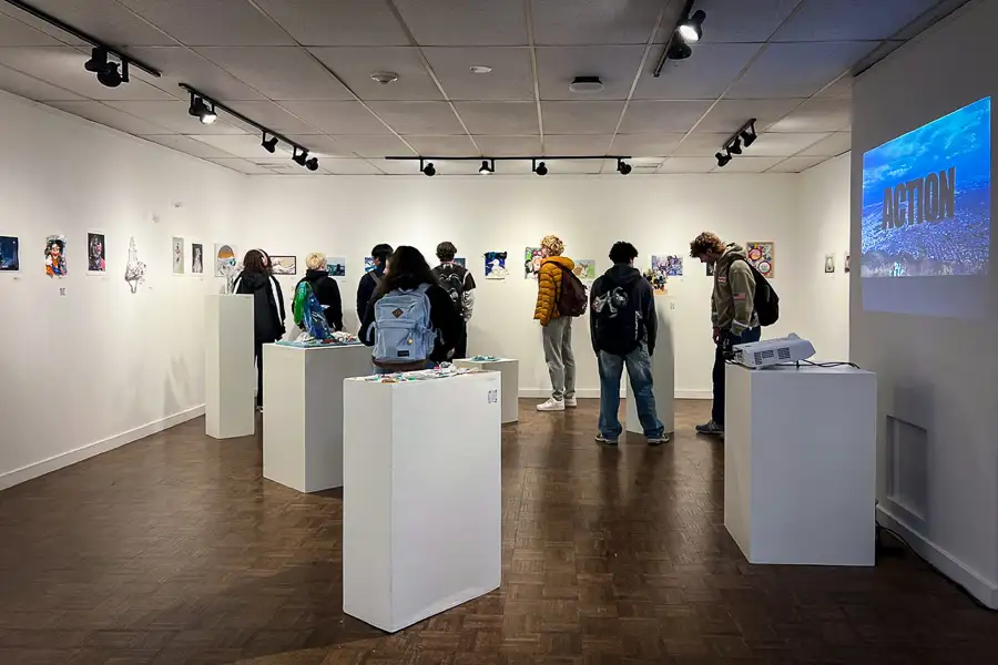 Estudiantes observan obras del proyecto Trash to Art durante la inauguración en la galería Winfisky de Salem State University.