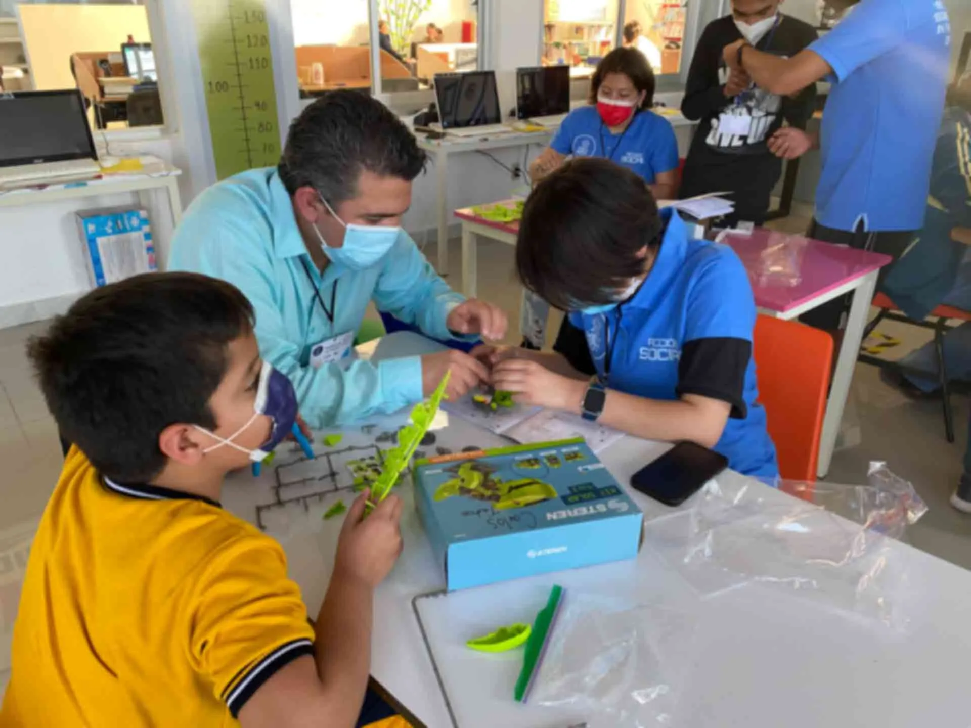 Ni&ntilde;os construyendo robot con ayuda de un adulto