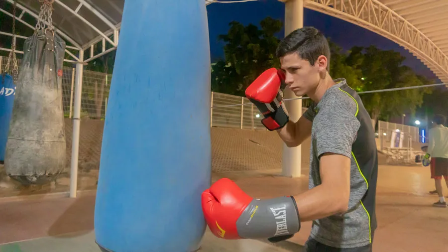 Joven deportista peg&aacute;ndole al costal durante entrenamiento de box