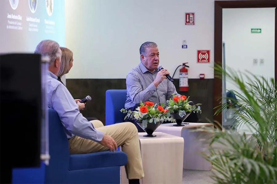 Empresario habla frente a un p&uacute;blico en p&aacute;nel de discusi&oacute;n.
