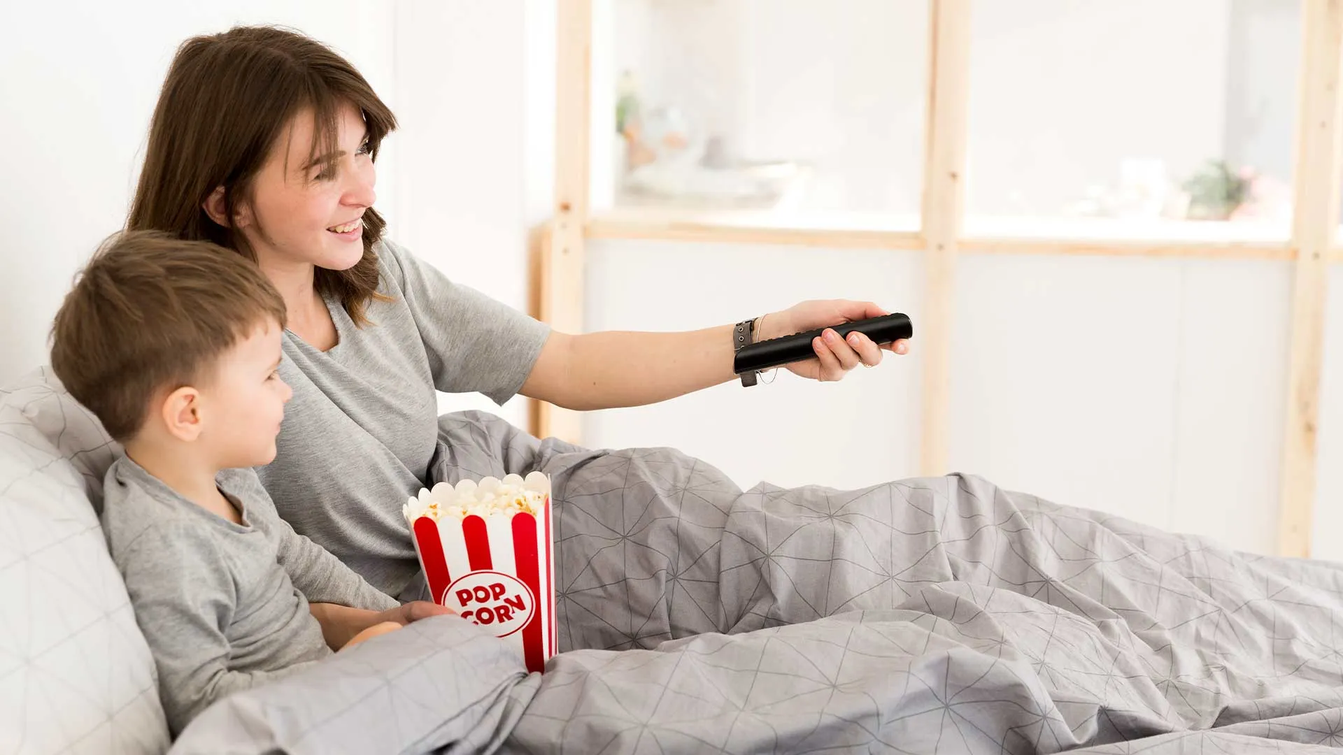 Mam&aacute; e hijo viendo una pel&iacute;cula desde su cama