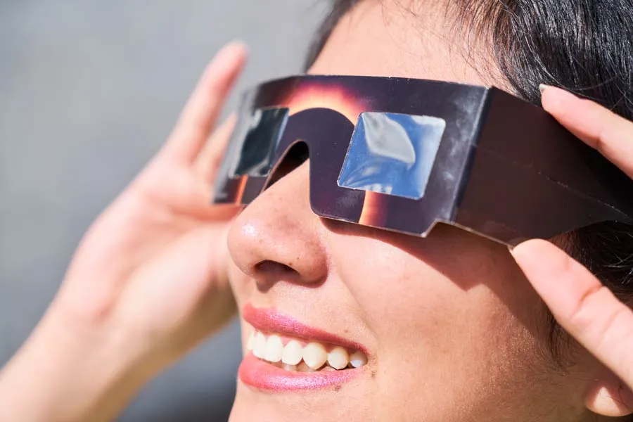 Mujer sonr&iacute;e viendo el eclipse solar.