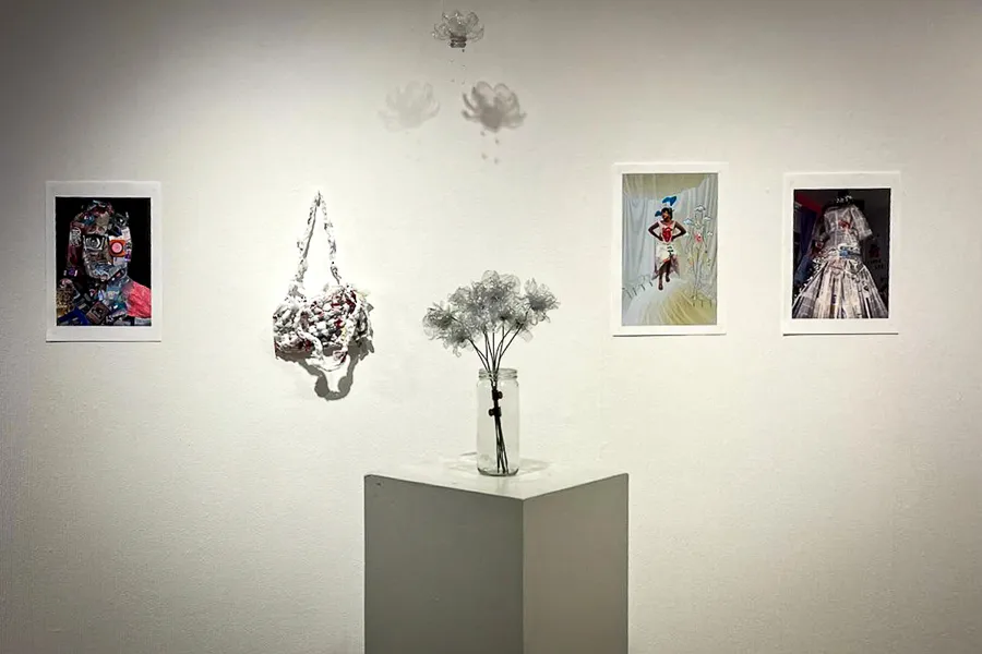 Obras realizadas con materiales reciclados en la exposición Trash to Art, incluyendo flores de plástico y una bolsa tejida.