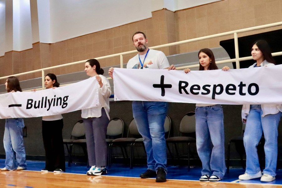 Docente y estudiantes de PrepaTec Chihuahua sostienen cartel de menos Bullying y más respeto en la presentación del programa Olweus.