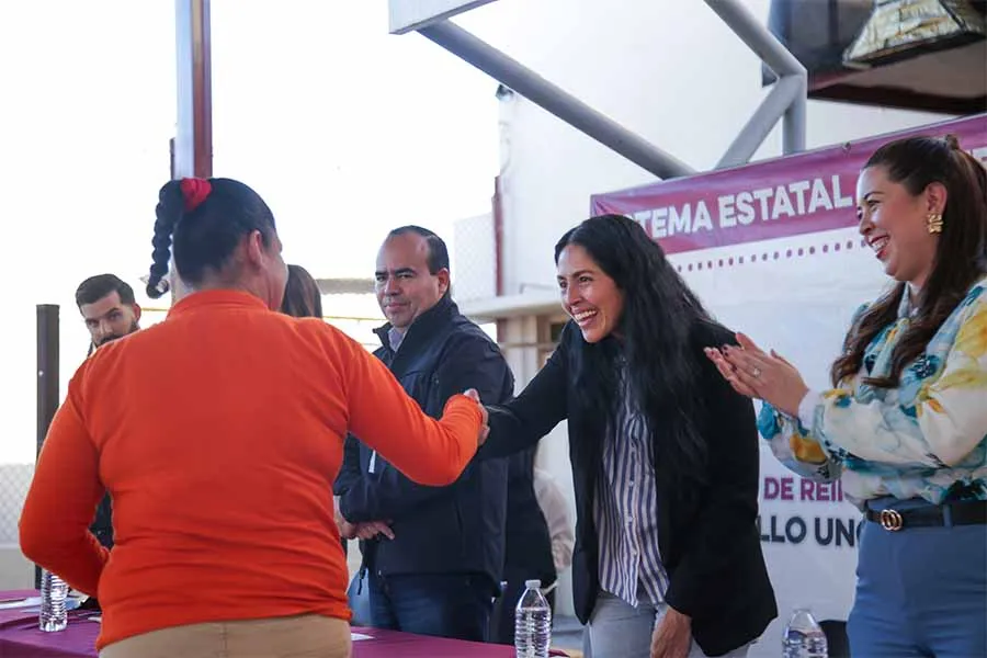 Una mujer interna del Cereso Femenil da la mano a directivos en ceremonia de graduaci&oacute;n.