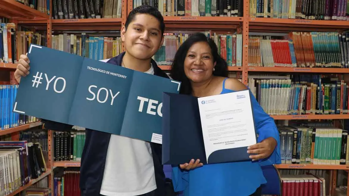 Estudiante de San Luis Potos&iacute; acepta la beca L&iacute;deres del Ma&ntilde;ana y posa para foto junto a su mam&aacute; en biblioteca.