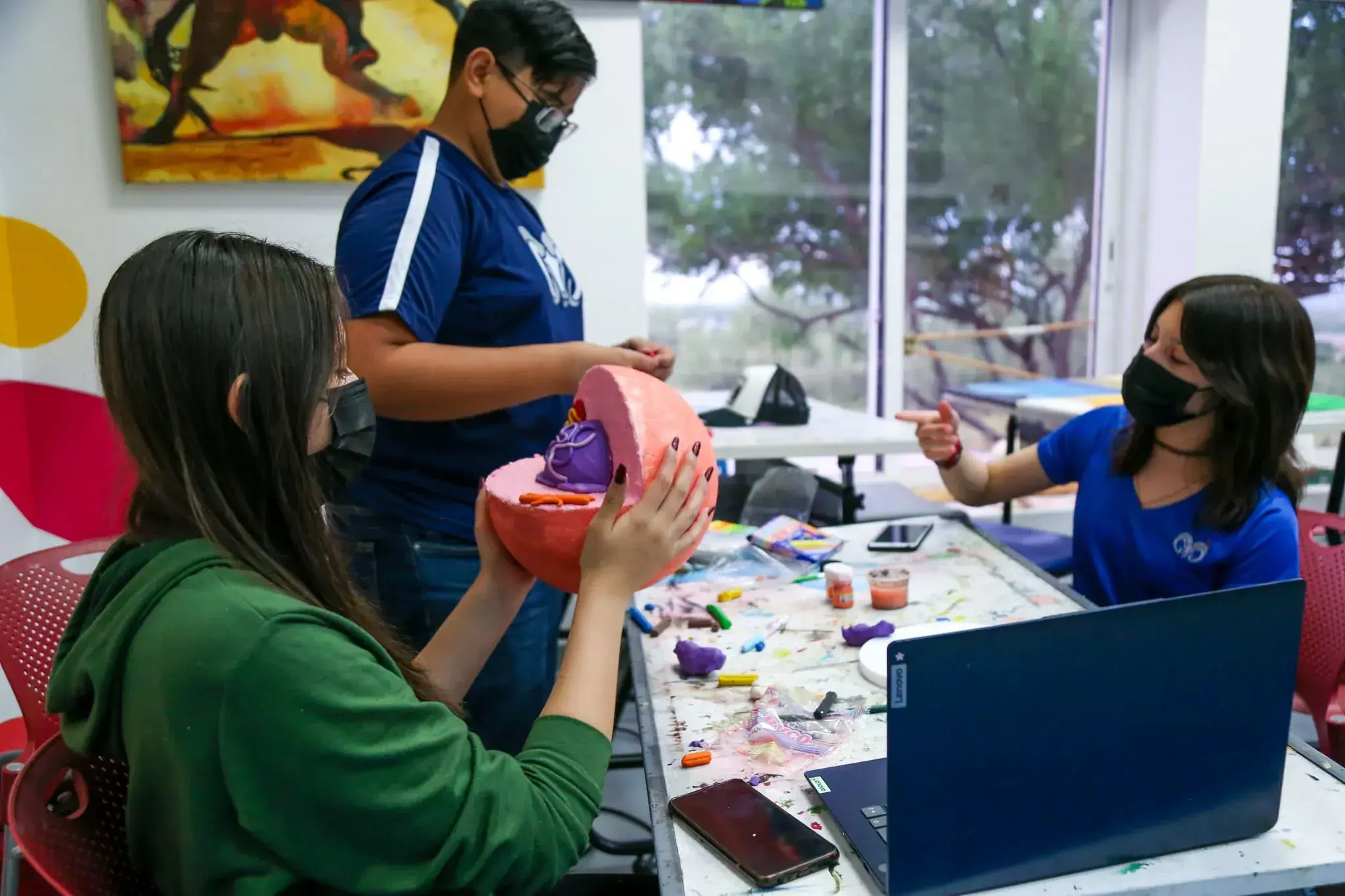 Alumnos pintando una escultura