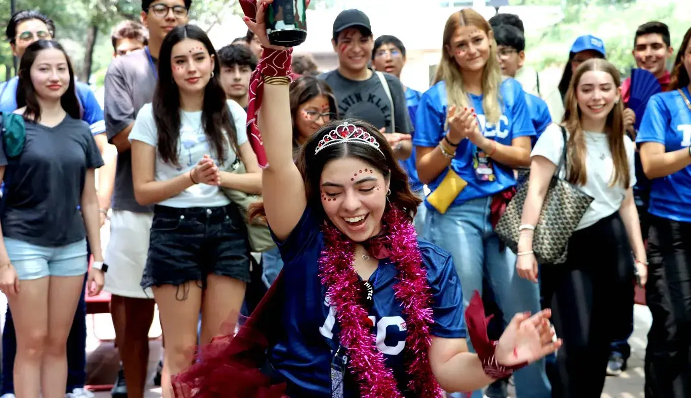 Alumna baila mientras alumnas y alumnos celebran.