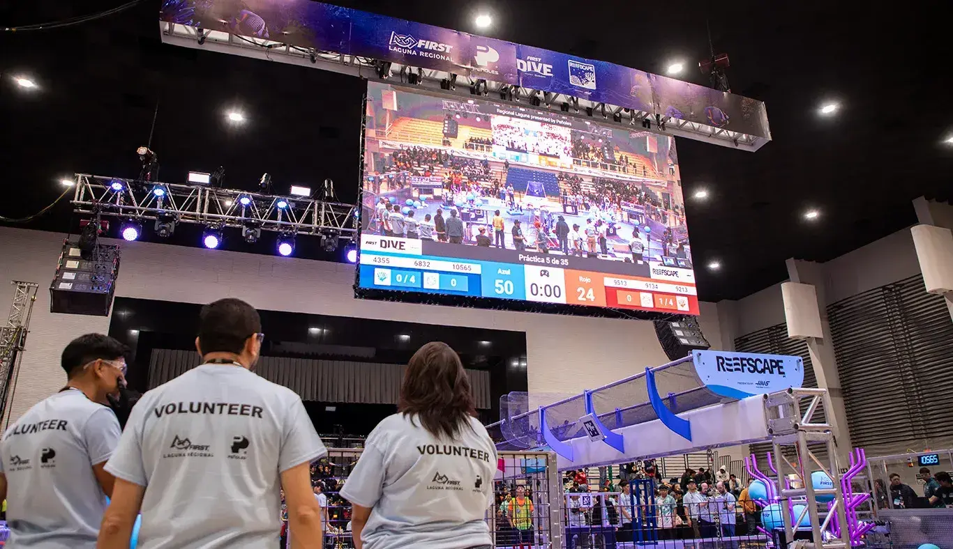 Voluntarios vigilan y apoyan a través de una pantalla lo que sucede en FIRST Regional Laguna 2025