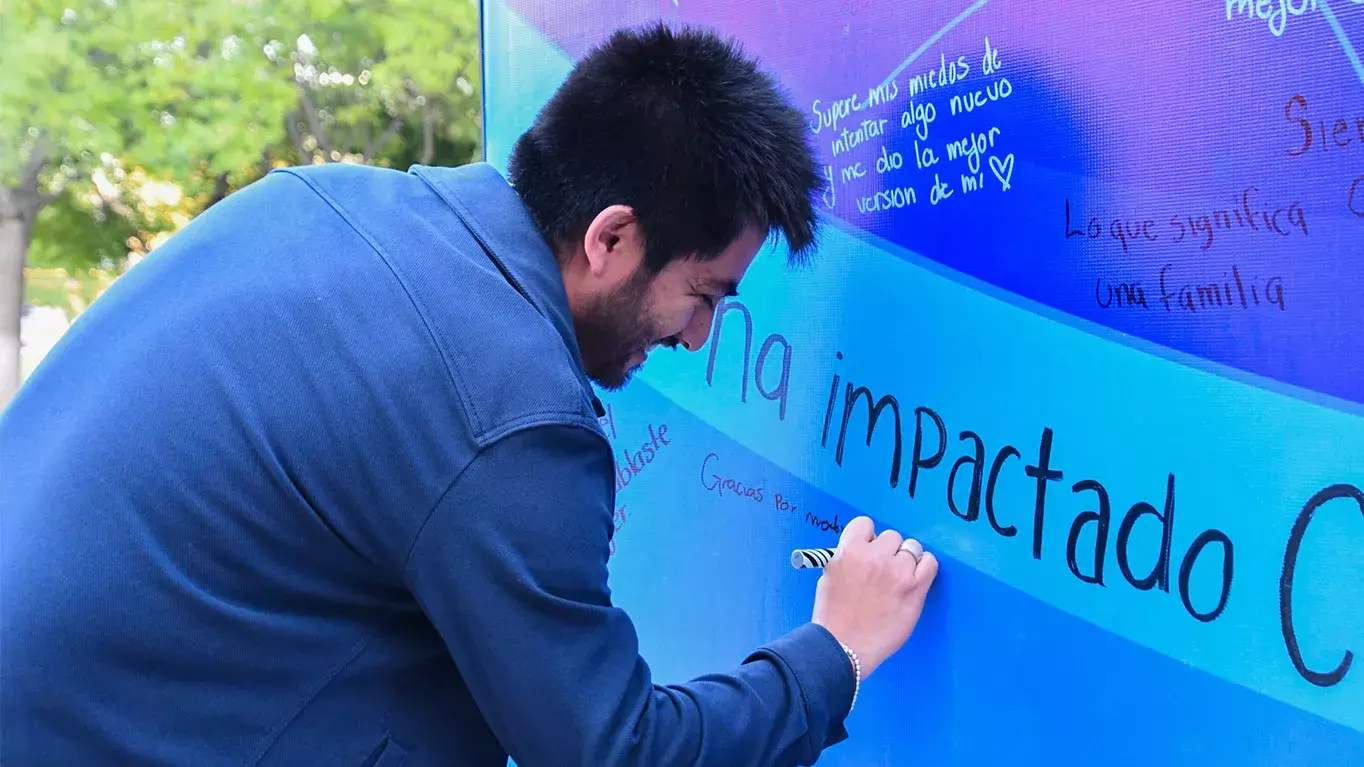 Alumno escribiendo en mural.