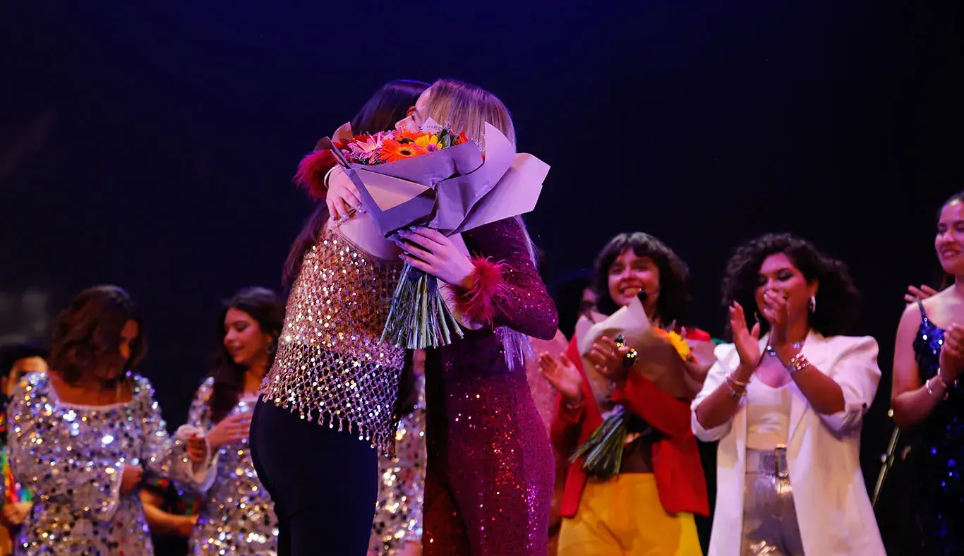 Estudiante recibiendo flores de profesora