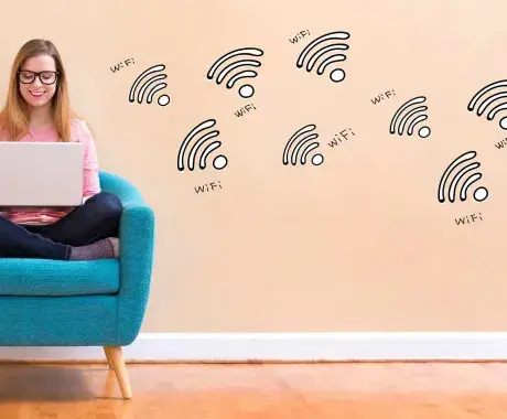 Mujer utilizando la computadora y en la pared aparecen iconos de conexión WiFi