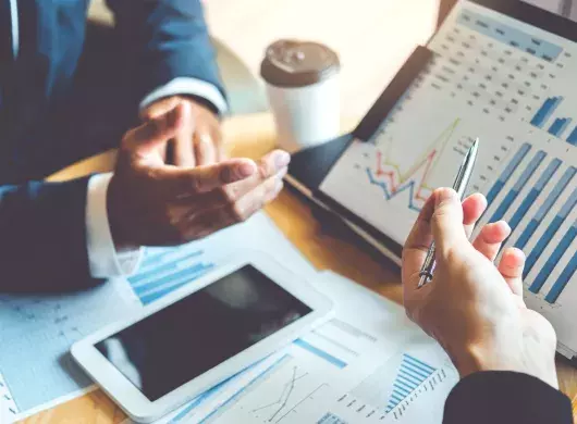 Personas analizando gráficos y datos financieros