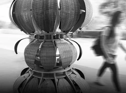 Foto en blanco y negro de la escultura con una persona caminando en el fondo.