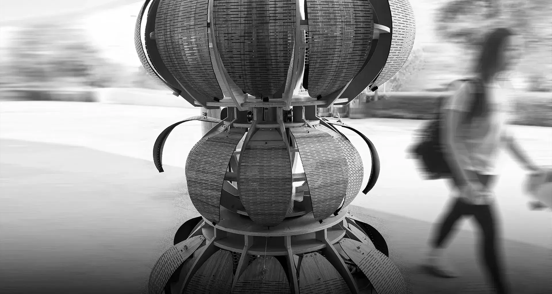 Foto en blanco y negro de la escultura con una persona caminando en el fondo.