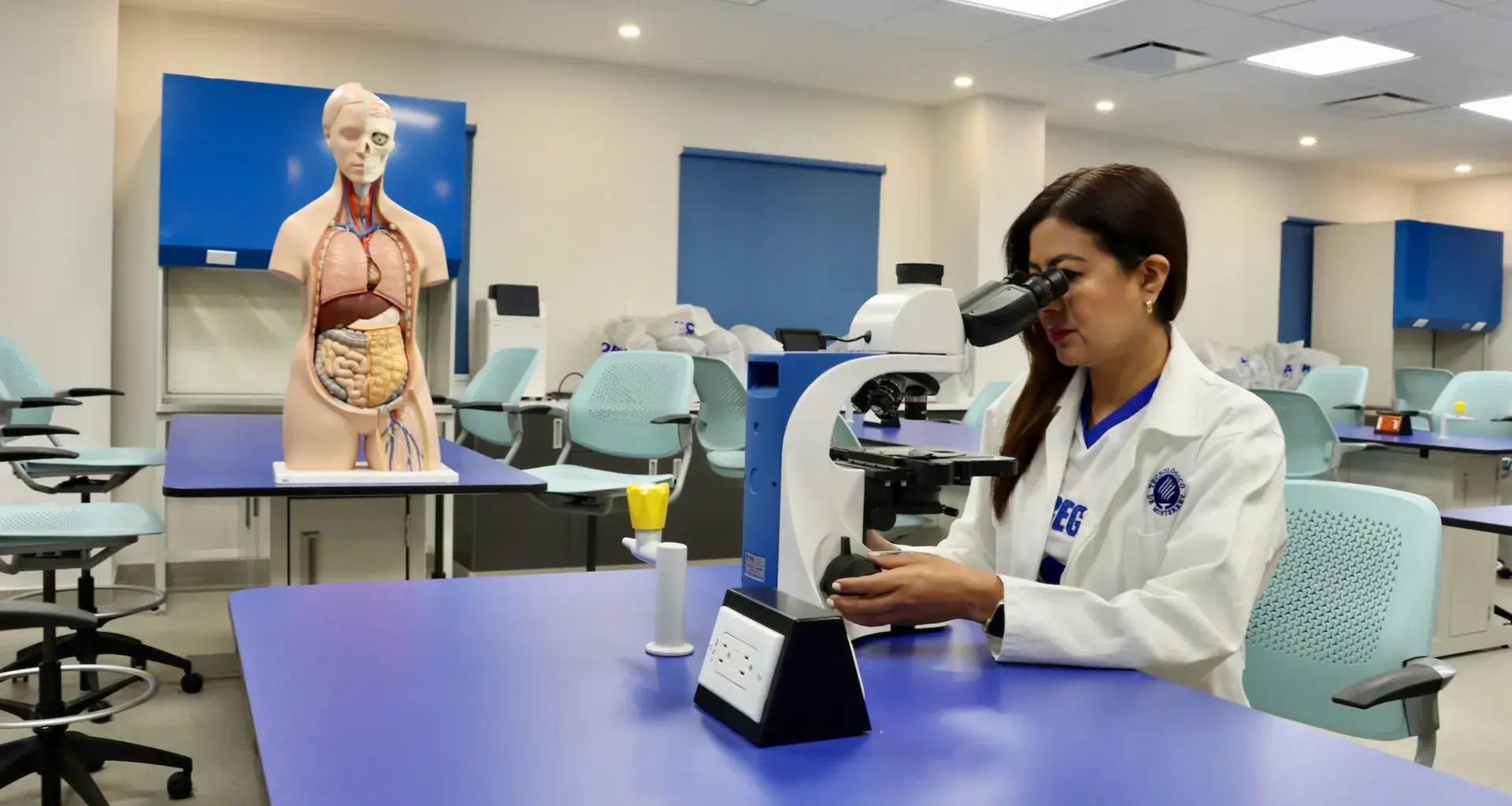 Karla Rojas observa una muestra a través de un microscopio en un laboratorio académico.