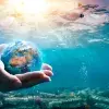 Imagen del mar contaminado con plástico, con una mano sosteniendo al mundo, conceptualizando el cuidado que requieren los océanos