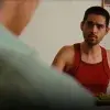 Vista sobre el hombro de una persona hacia un joven sentado en una mesa. 