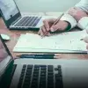 Superficie de una mesa con laptops y papeles.