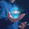 Un hombre de negocios sosteniendo un globo de IA holográfica brillante con 2026 e inteligencia artificial, computación en la nube, red neuronal e iconos de ciberseguridad, que representan la tecnología futura. Tendencias de la IA en 2026.