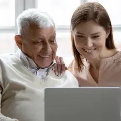 Adulto mayor y mujer joven usando una laptop