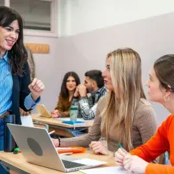 Profesora interactuando con 2 estudiantes jóvenes