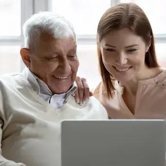 Adulto mayor y mujer joven usando una laptop