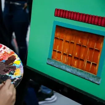 Alumna pintando una ventana sobre un fondo verde