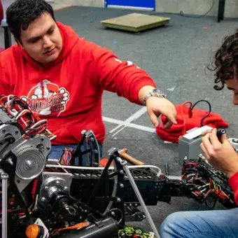 El coach Francisco Rosas ayudando a un estudiante con el robot.