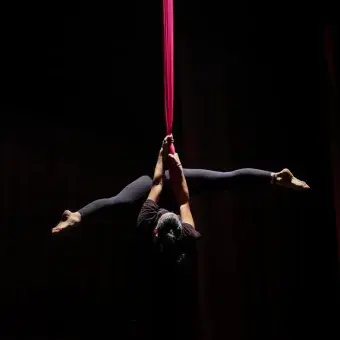 Chica de cabeza colgada de telas en número de danza aérea. 