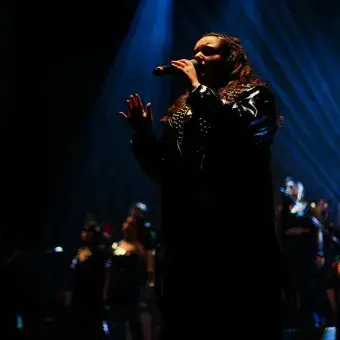 Cantante vestida de negro con luz iluminando su cara. 