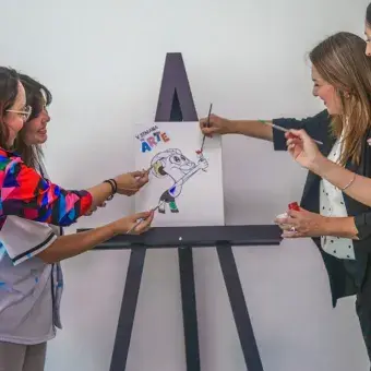 Catro mujeres pintando sobre un bastidor con una imagen de Teus.