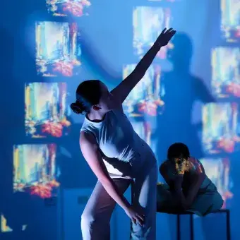 Alumna posando frente a una proyección de obras artísticas.