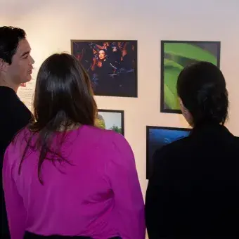Tres personas de espaldas contemplando una exposición de fotos.