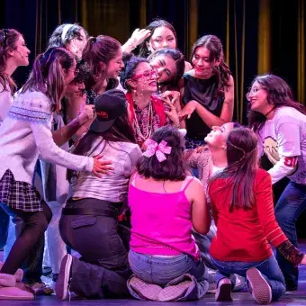 Estudiantes interpretan una escena de la clase de teatro dirigida por la señora Darbus durante el musical High School Musical: On Stage, caracterizados con vestuario expresivo y actitudes teatrales.