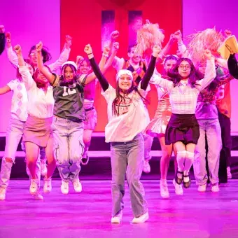Estudiantes del Tec de Monterrey realizan una coreografía grupal durante un número musical de High School Musical: On Stage, con vestuarios escolares y expresión escénica activa.