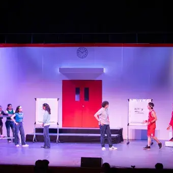 Escena del musical High School Musical: On Stage donde los personajes se preparan simultáneamente para el concurso de ciencias y el campeonato de baloncesto, con ambos grupos distribuidos a los extremos del escenario.