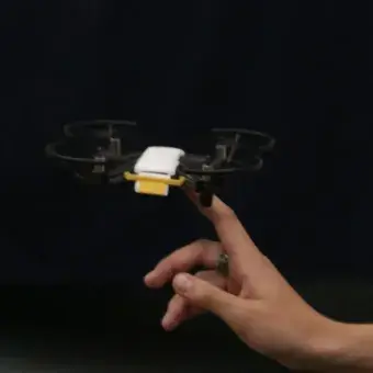 Drone volando y estudiante manipulandolo.