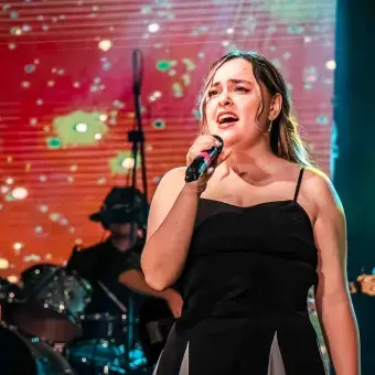 Jóven mujer solista con vestido negro interpreta canción en ensamble musical del 50 aniversario del Tec de Monterrey campus Laguna