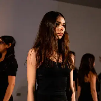 Tres chicas vestidas de negro dándose la espalda mutuamente.
