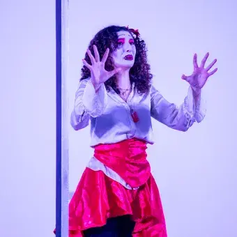 Chica con maquillaje dramático parada frente a un marco de espejo.